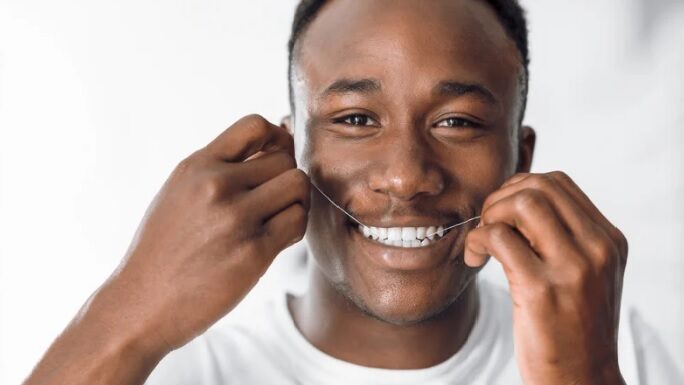 A Young man flossing his teeth with string floss